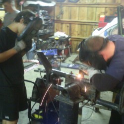 Gary welding the beam while Paul observes with a welding masks.