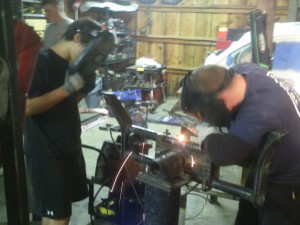 Gary welding the beam while Paul observes with a welding masks.